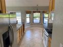 Well-lit kitchen with tile floors, light wood cabinets, and stainless steel refrigerator at 1011 Chance Cv, Oviedo, FL 32765