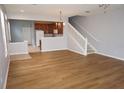 Open-concept living area with wood floors, stairs, chandelier, and seamless transition to kitchen at 1034 Enclair St, Orlando, FL 32828