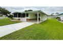 Well-manicured light green house with carport and concrete driveway at 106 Azalea Trl, Leesburg, FL 34748
