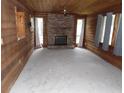 Cozy living room featuring wood-paneled walls, a brick fireplace, and large windows with light-filtering curtains at 360 Kentia Rd, Casselberry, FL 32707