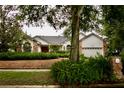 Charming single-story home showcasing a well-manicured lawn, mature trees, and a two-car garage at 8044 Rural Retreat Ct, Orlando, FL 32819