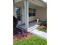 Cozy covered porch with a decorative leaded glass front door and tidy landscaping at 527 San Pedro Dr, The Villages, FL 32159
