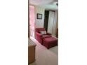 Comfortable bedroom with a cozy armchair, ottoman, and a glimpse into an attached bathroom at 804 Maple Ln, Lady Lake, FL 32159