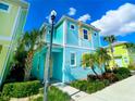 Two-story light teal home with yellow and green neighbors, palm trees, and a sidewalk at 2968 Salted Rim Rd, Kissimmee, FL 34747