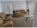 Cozy living room featuring neutral-toned furniture, glass-topped tables, and natural light from window blinds at 959 Nancy Ct, Kissimmee, FL 34759