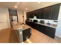 Modern kitchen with sleek black cabinetry, granite countertops, and stainless steel appliances at 2585 Needlepoint St, Kissimmee, FL 34741