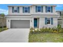 Charming two-story home with blue shutters, a well-manicured lawn, and a gray two-car garage at 1715 Sugarbelle Cir, Mascotte, FL 34753