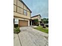 Tan two-story townhouse with brown garage door and landscaping at 2031 Balboa Way, Kissimmee, FL 34741