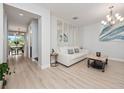 Bright living room with light floors, white sofa, and a decorative mirror at 3241 Wauseon Dr, Saint Cloud, FL 34772