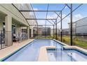 Backyard pool features a screened enclosure, a patio lounge area, and green lawn at 4348 Quote St, Kissimmee, FL 34746