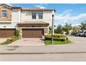 Two-story townhome featuring a brick driveway, stone accents, and a well-manicured lawn at 8541 Spyglass Ln, Davenport, FL 33896