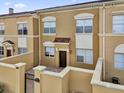 Townhouse with light brown stucco, red-tiled roof, white window frames, private gated entrance and small patio at 2774 Bella Vista Dr, Davenport, FL 33897