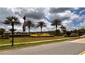 Welcoming community entrance featuring lush landscaping, elegant signage, and palm trees against a cloudy sky at 1515 Carey Palm Cir, Kissimmee, FL 34747