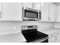 Stainless steel range and microwave installed above in white kitchen at 2930 Sharp Rd, Kissimmee, FL 34744