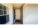 View of the covered front porch featuring an open front door, tile floor and exterior sconce lighting at 5317 Micco St, Kissimmee, FL 34746