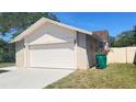 Home featuring a two-car garage and green lawn on a sunny day, perfect for suburban living at 5317 Micco St, Kissimmee, FL 34746
