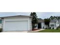 Front view of a single story home with a white exterior, attached garage, and landscaping at 325 Ashley Loop, Davenport, FL 33837