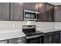 Sleek kitchen with dark cabinetry, stainless steel appliances, and white countertops at 911 Heirloom Dr, Haines City, FL 33844