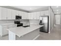 Modern kitchen with white cabinets, stainless steel appliances, and an island at 930 Heirloom Dr, Haines City, FL 33844