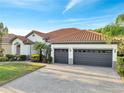 Lovely single-story home featuring a tile roof, a three-car garage, and a paved driveway at 2891 Swoop Cir, Kissimmee, FL 34741