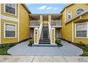 Exterior view of a yellow two-story building with stairs and landscaping at 8718 Rain Forest Pl # C, Kissimmee, FL 34747