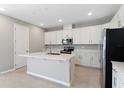 Bright kitchen featuring white cabinets, stainless steel appliances, a large island, and light tile floors at 4220 Sawtooth Ct, Tavares, FL 32778