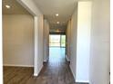 A well-lit hallway with wood-look tile flooring leads to a bright living space with sliding glass doors at 4520 Gliding Wave St, Winter Garden, FL 34787