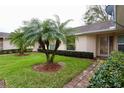 Landscaped front yard featuring green grass, palm trees, trimmed shrubs and a brick walkway leading to front door at 2724 Shelby Ruth Pl, Saint Cloud, FL 34769