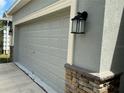 This home's garage door is a classic style with decorative paneling, complemented by an elegant lantern at 4183 Cortland Dr, Davenport, FL 33837