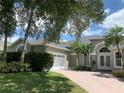 Well-manicured lawn and greenery enhance the home's curb appeal, with a view of the paved drive and garage at 14421 Hatchee Ct, Orlando, FL 32837