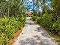 Long gravel driveway leads to a brick home surrounded by lush greenery and mature trees at 1775 Sundance Dr, St Cloud, FL 34771