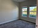 Bright bedroom with neutral walls, plush carpet, and natural light from two windows at 1077 Quaker Ridge Ln, Davenport, FL 33896