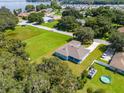Aerial view of a light blue home with a sprawling green lawn, boat, and pool in a lakeside community at 319 Water Shore Dr, Leesburg, FL 34748