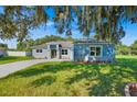 Charming single-story home with a well-manicured lawn and a light blue exterior and stone accents at 319 Water Shore Dr, Leesburg, FL 34748