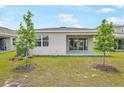 Spacious backyard featuring a covered patio and well-maintained lawn perfect for entertaining or relaxing with two shade trees at 196 Flag Lilly Ln, Umatilla, FL 32784