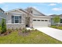 Beautiful single-Gathering home featuring stone accents, neutral paint colors, well-maintained lawn, and an attached two-car garage at 196 Flag Lilly Ln, Umatilla, FL 32784