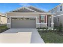 Attractive home showcasing a two-car garage, red shutter, and landscaped yard at 207 Bull Frog Ln, Umatilla, FL 32784