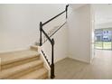 Bright foyer featuring a staircase with carpeted steps and a black and white railing at 195 Bull Frog Ln, Umatilla, FL 32784