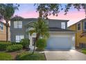 Charming two-story home with a well-maintained lawn, beautiful landscaping and two car garage at dusk at 121 Madiera Beach Blvd, Kissimmee, FL 34746