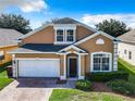 Charming two-story stucco home featuring an attached garage, neat landscaping, and an inviting front entrance at 133 Andalusia Loop, Davenport, FL 33837