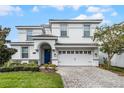 Charming white two-story home featuring an arched entryway, tidy landscaping, and a paved driveway at 9099 Hazard St, Davenport, FL 33896