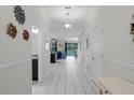 Bright hallway featuring elegant white tile floors, crown molding, and an open view into the living and dining areas at 9099 Hazard St, Davenport, FL 33896