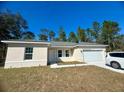 Tan house with gray roof, white garage door, and landscaping at 6809 149Th Lane Rd, Ocala, FL 34473