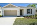 The front exterior features neutral tones, a two-car garage, a well-manicured lawn and an inviting front door at 1655 Sugarbelle Cir, Mascotte, FL 34753