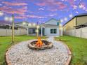 A cozy backyard featuring a fire pit, string lights, a screened patio, and a well-maintained lawn at 5249 Villa Rosa Ave, St Cloud, FL 34771
