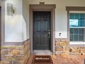 A welcoming front door with stylish stone accents and a 'Welcome' mat on a brick-paved porch at 5249 Villa Rosa Ave, St Cloud, FL 34771