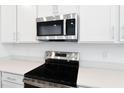 Close-up of stainless steel oven and microwave with white countertops and cabinets at 1753 Carnelian St, Deland, FL 32720