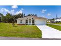 Inviting single-story home with manicured lawn, colorful flowerbeds, and attached two-car garage on a sunny day at 1415 Orlando Way, Kissimmee, FL 34759