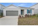 Charming single-story home featuring a grey garage door, blue door, and manicured landscaping at 5410 Catmint Dr, Lake Hamilton, FL 33851