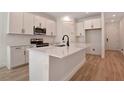 Modern kitchen features white cabinets, stainless steel appliances, and a large center island with sink and black faucet at 4064 Bannock Ave, Tavares, FL 32778